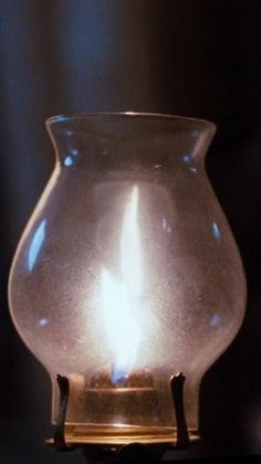 a lit candle in a glass vase on a table