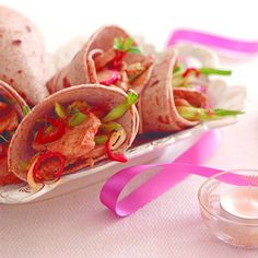 three tacos with meat and vegetables on a plate next to a glass of milk