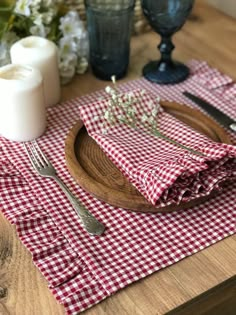 a red and white checkered table cloth on top of a wooden plate with silverware