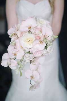 a bride holding a bouquet of pink and white flowers