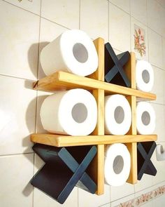 several rolls of toilet paper sitting on top of wooden shelves in a tiled bathroom wall