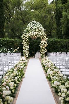 an outdoor ceremony with white flowers and greenery