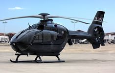 a black helicopter sitting on top of an airport tarmac