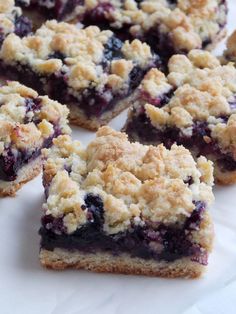 blueberry crumb bars stacked on top of each other next to a bowl of fresh blueberries