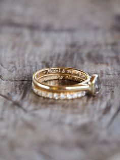 two gold wedding rings sitting on top of a wooden table