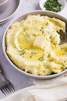 mashed potatoes with butter and parsley in a white bowl on a marble table