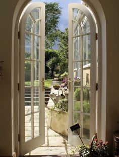 an open door leading to a patio with potted plants