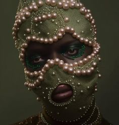 a woman with pearls on her face and green eyes, wearing a mask made out of pearls