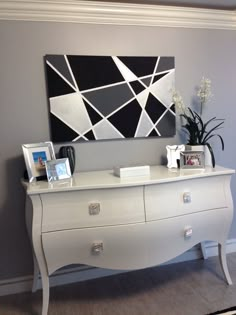 a white dresser sitting in front of a painting