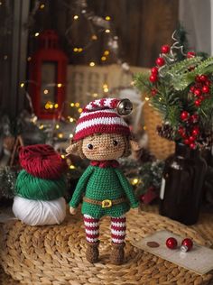 a crocheted doll sitting on top of a wicker basket next to christmas decorations