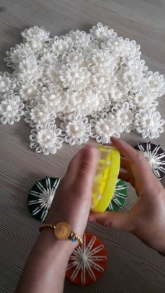 a person holding a yellow object in their hand and some white flowers on the table