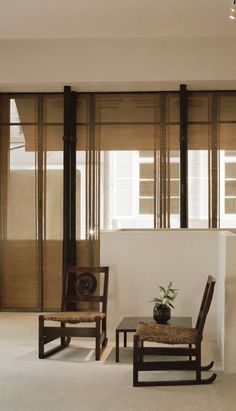 two chairs and a table in a room with wooden blinds on the windowsills