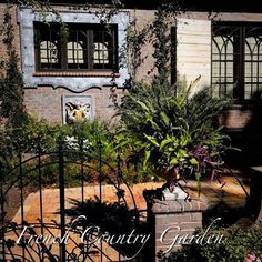 an iron gate in front of a brick building with plants and potted plants on it