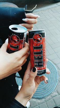 two women holding cans of red bull beer