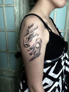 a woman wearing a black and white dress has a tattoo on her arm with hands holding keys