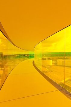 an empty walkway in front of a glass wall with yellow and green reflections on it