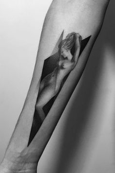 a black and white photo of a woman's arm with an origami tattoo