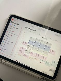 a tablet with a calendar on the screen sitting on top of a white tablecloth