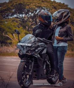 two people standing next to each other on a motorcycle