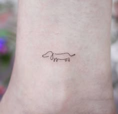 a small tattoo on the ankle of a woman's leg that has a dachshund drawn on it