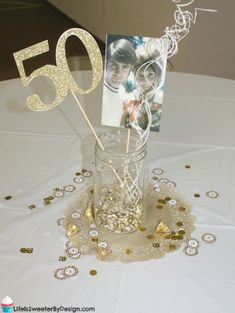 a table topped with a mason jar filled with gold confetti and a card