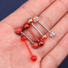 four red and white flowered bobby pins on a person's hand