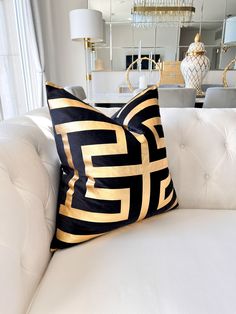 two black and gold pillows sitting on top of a white couch in a living room