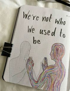 an open notebook with a drawing of two people holding hands and the words we're not who we used to be