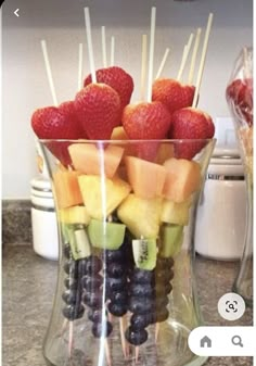 fruit is arranged on sticks in a glass bowl with strawberries, grapes, and melon