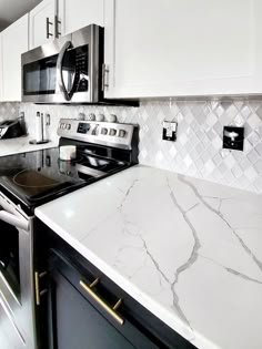 a kitchen with white marble counter tops and stainless steel stove top oven, microwave and dishwasher