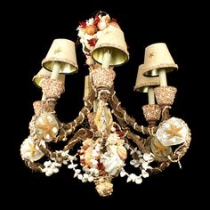 a chandelier with three lamps and flowers on it