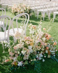 an arrangement of flowers on the ground in front of rows of chairs at a wedding