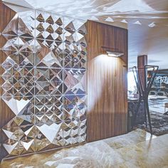 a room divider made out of mirrored tiles and wooden paneling, with an abstract design on the wall