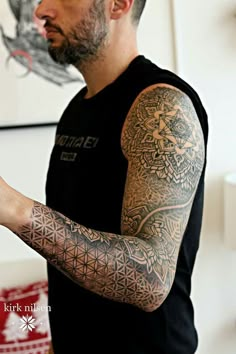 a man with tattoos on his arm holding a cell phone