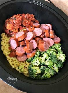 a bowl filled with pasta, sausage and broccoli on top of a table