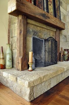 a stone fireplace in a living room with wood flooring and decor on the mantle