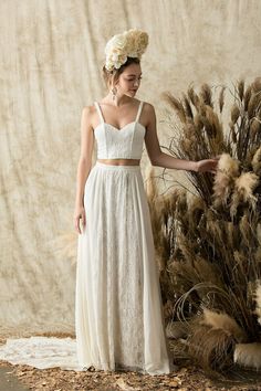 a woman in a white dress standing next to dried plants