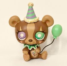 a small toy bear with big eyes and a party hat on it's head