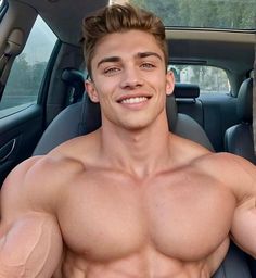 a shirtless man sitting in the back seat of a car with his hands on his hips