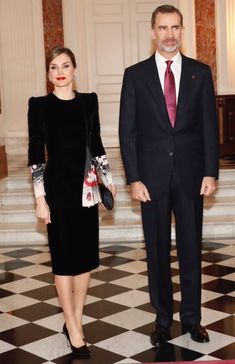 the man and woman are standing next to each other in front of a black and white checkered floor