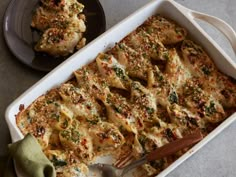 a casserole dish with chicken and cheese in it, next to a fork