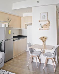 a kitchen and living room with wood flooring, white walls and furniture in it