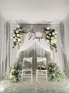 two white chairs sitting under a wedding arch