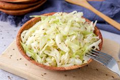 a wooden bowl filled with coleslaw on top of a cutting board