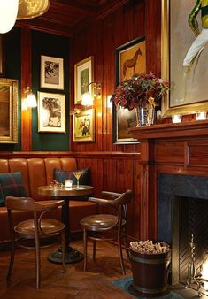 a restaurant with wood paneling and leather seating, including two round tables in front of a fireplace