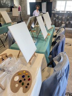 a woman standing in front of an easel with paint on it