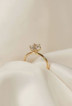 a gold ring with two diamonds on it sitting on top of a white cloth covered surface