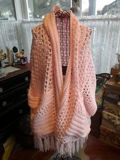 a pink crocheted shawl draped over a table