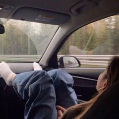 two people sitting in the back seat of a car with their feet propped up on the dashboard