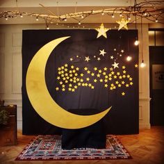 a large black and yellow moon with stars hanging from it's side on a rug